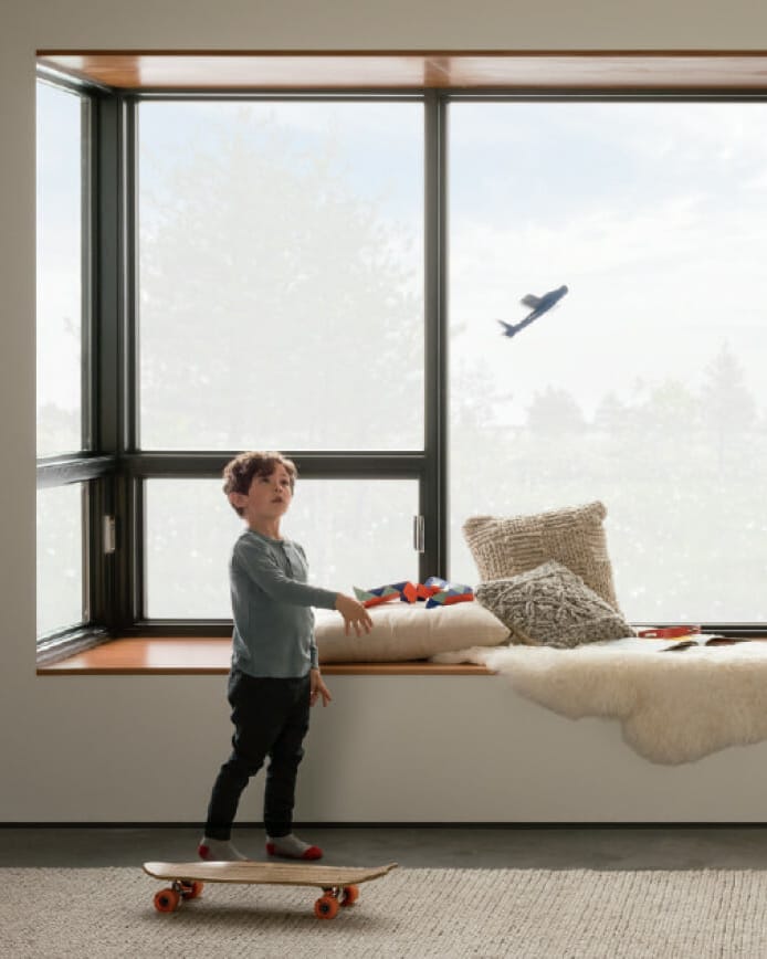 Boy in living room throwing model airplane in air