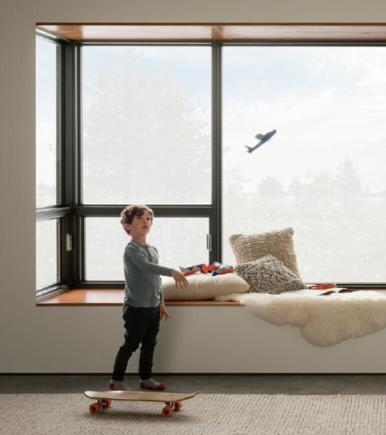 Boy in living room throwing model airplane in air