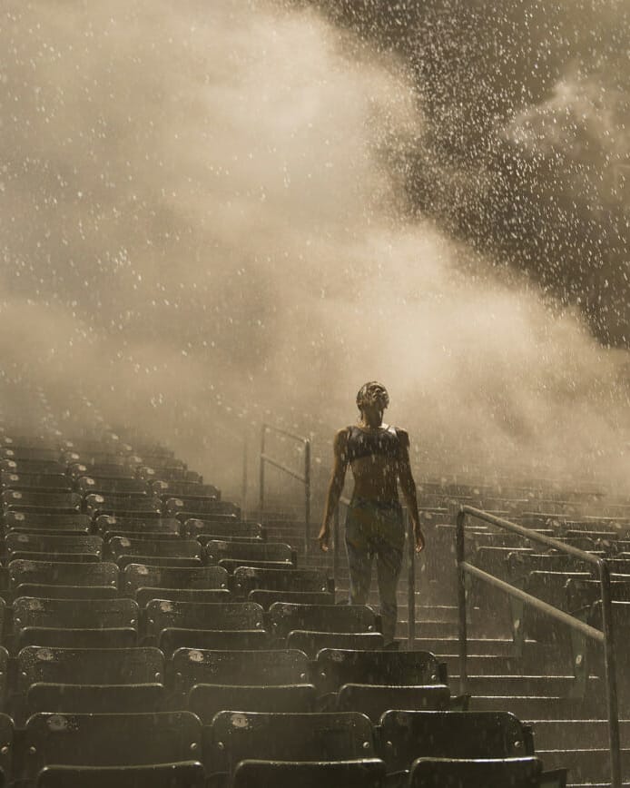 Female running athlete training on bleachers in rain