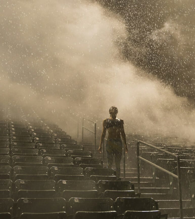 Female running athlete training on bleachers in rain