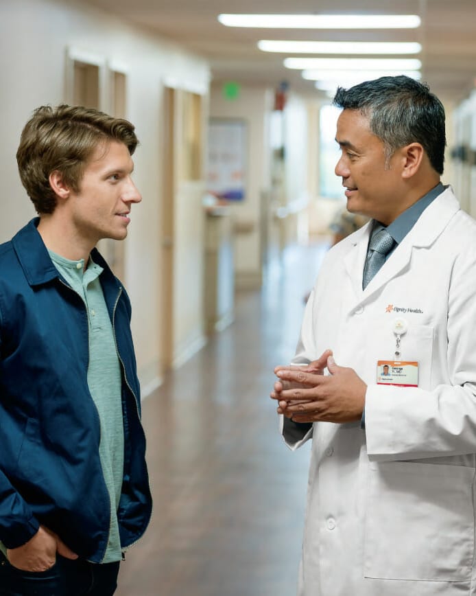 Young man speaking with doctor in hallway of hospital