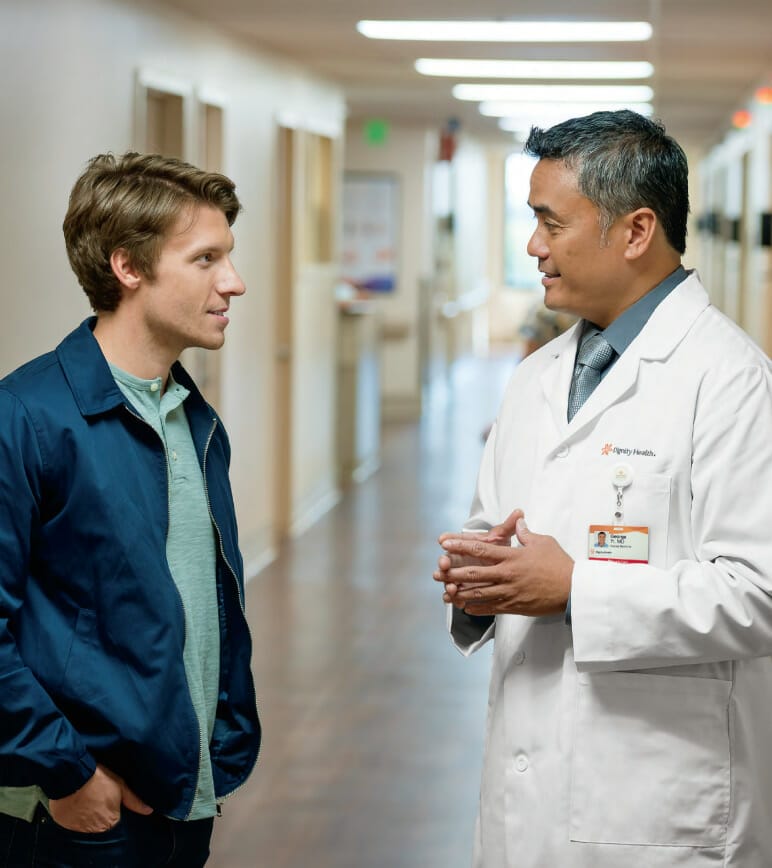 Young man speaking with doctor in hallway of hospital
